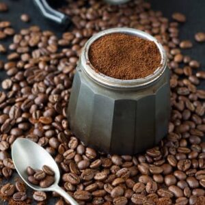 Grain de café avec avec cafétière ouverte et café moulu dedans