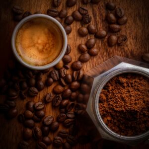 graine_de_cafe_sur_table_avec_cafetière_et_cafe_moulu_et_tasse_de_cafe